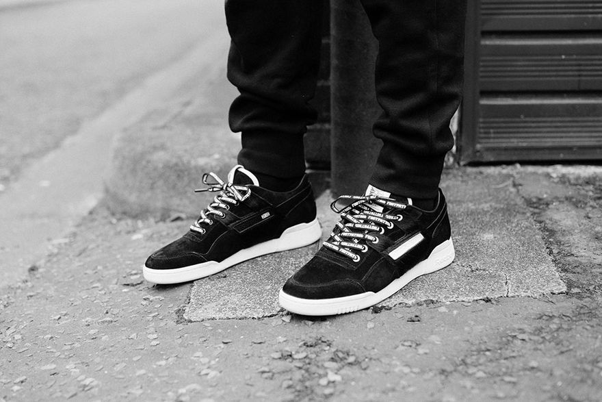 Schwarze Reebok x Footpatrol Workout Lo Blackbuck am Fuß, Schwarzweiß-Foto auf der Straße